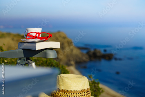 Coffee cup and book on sea coast. Relax
