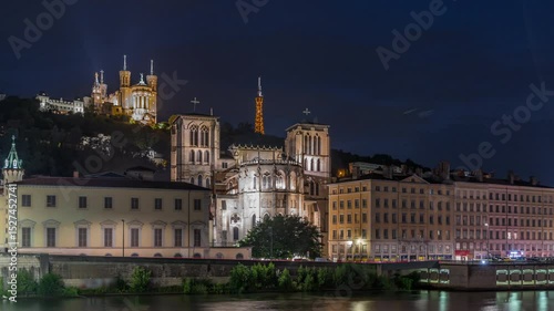 Timelapse of Saint John the Baptist Cathedral and Basilica of Notre-Dame de Fourviere in Lyon, transitioning from day to night. Illuminated waterfront and buildings at the river. France