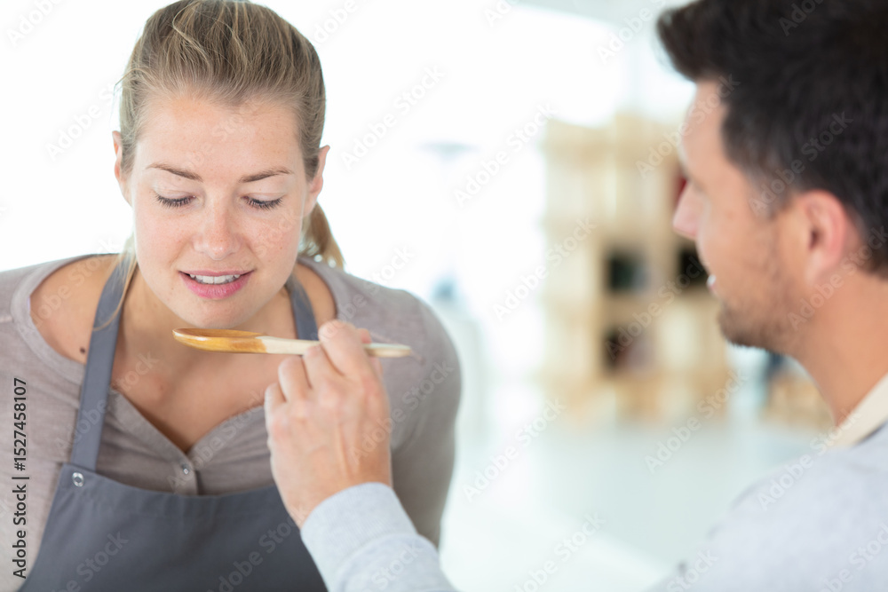 Obraz premium couple tasting food from wooden spoon