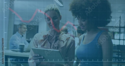Two businesswomen touching tablet screen and tracking fading red line graph animating sales data