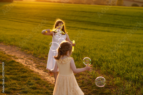Two children girls playing with bubbles at sunset.