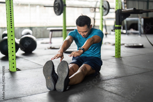 Fitness Stretching Exercise. Young man reaching for his toes on the gym floor.