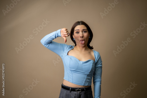 Mujer con pulgares abajo y cara graciosa de disgusto