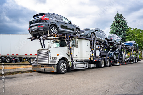 Obraz na płótnie Loaded car hauler white big rig semi truck with two semi trailers standing on th