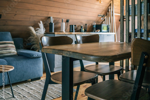 Wallpaper Mural Close-up of modern wooden dining table and chairs in cozy Scandinavian style kitchen with wooden walls, blue sofa, and kitchen countertop Torontodigital.ca