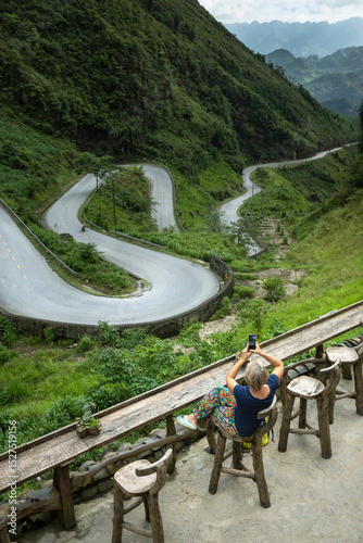 Solo female traveler taking a photo at the famous Nine-Turn viewpoint of Ha Giang loop in northern Vietnam