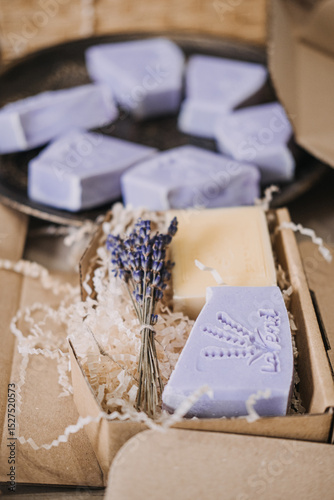Handmade lavender soaps packed in kraft boxes with shredded filler in a cozy workspace. Home-based business, handmade skincare, small batch production, eco-friendly packaging