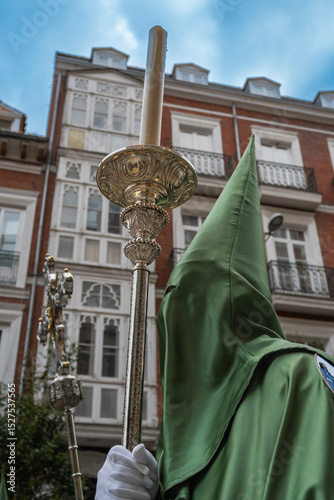 Semana santa Valladolid. Primer plano de cofrade con capirote verte y báculo con cirio