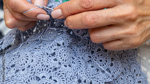 Close up of hands of unrecognizable woman knitting handmade clothes with spokes using  wool yarn. Concept of leisure activity.Knitting from yarn on  coarse spokes.
