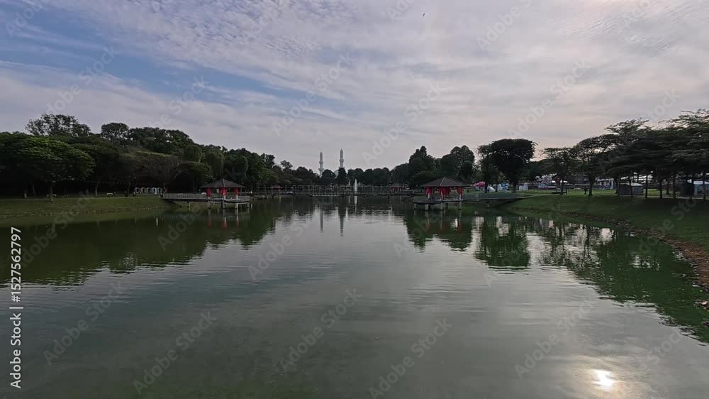 A tranquil lake in a tropical public park surrounded by lush greenery. Visitors enjoy recreation and relaxation in this serene setting. A tranquil lake in a tropical public park surrounded by lush greenery. Visitors enjoy recreation and relaxation in this serene setting.