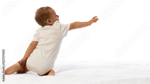 Fotografie Rear view photo of small kid, toddler boy kneeling reaching forward with extended hand against white background with copy space