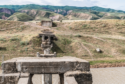 View of old broken irrigation aqueduct and green hills in Chui region of Kyrgyzstan.
