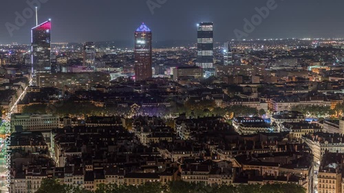 Panoramic aerial view of Lyon with skyscrapers from Fourviere Hill at night. The skyline features Rhone River and iconic city landmarks illuminated at evening. Houses rooftops and traffic on streets