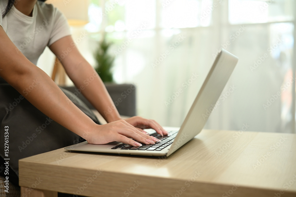 Fototapeta premium Close-up of a teenage girl hands using a laptop, A cozy home study space, Remote Work and Study Setup Concept