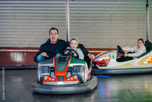 Father and daughter enjoying bumper cars at amusement park