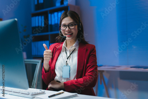 Asian businesswoman showing thumbs up working overtime in office at night
