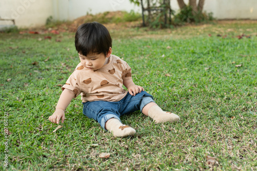 Asain baby boy sitting and playing on green grass