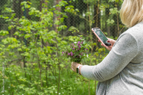 Woman holding a bouquet of wildflowers and a smartphone in a forest