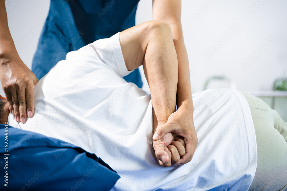 Fototapeta premium Male physiotherapist performs spine and arm adjustment therapy for patient on bed. Manual therapy, pain relief, posture alignment