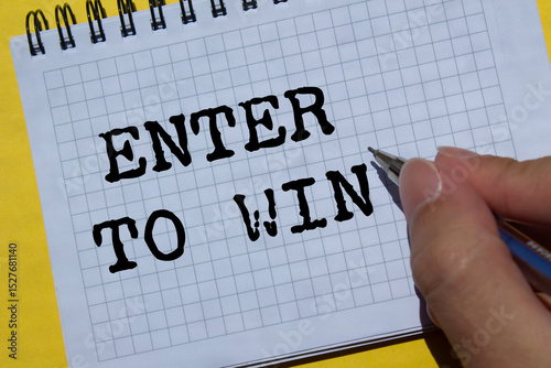 Enter to win message written on notebook page on yellow background. Conceptual enter to win symbol. Copy space.