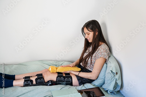 Teen girl with broken leg using a hot water bottle while resting