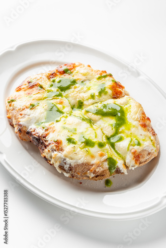 Photography Rectangular pizza with melted cheese and green pesto sauce on a white oval plate