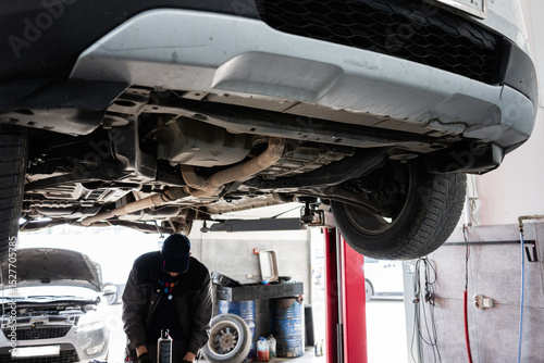 Mechanic inspecting vehicle underside on lift in automobile repair shop photo