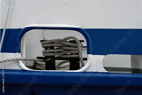 Cable rope wound round cleat on a blue and white boat