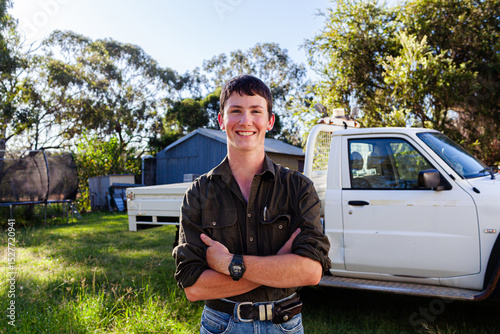 Portrait of happy smiling teenaged young person standing by ute in country - trade apprentice photo