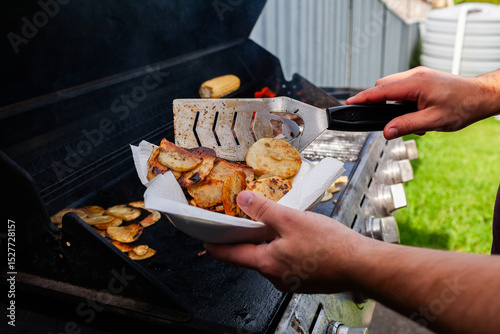 Man finishing cooking home made potato chips on backyard barbecue photo