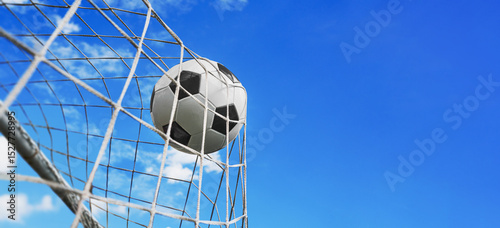  Soccer ball in soccer goal net in a big stadium isolated on blue sky. soccer net. Big panorama with copy space.