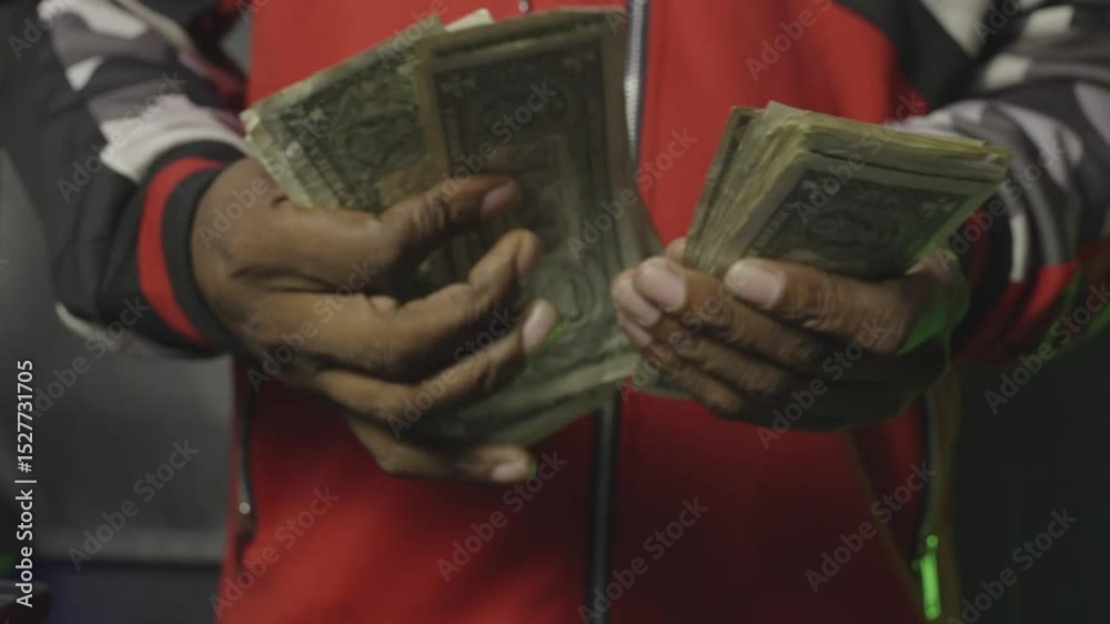 Close-up of hands flipping through stacks of worn dollar bills in a red-and-black jacket, showcasing street hustle and gritty cash flow.