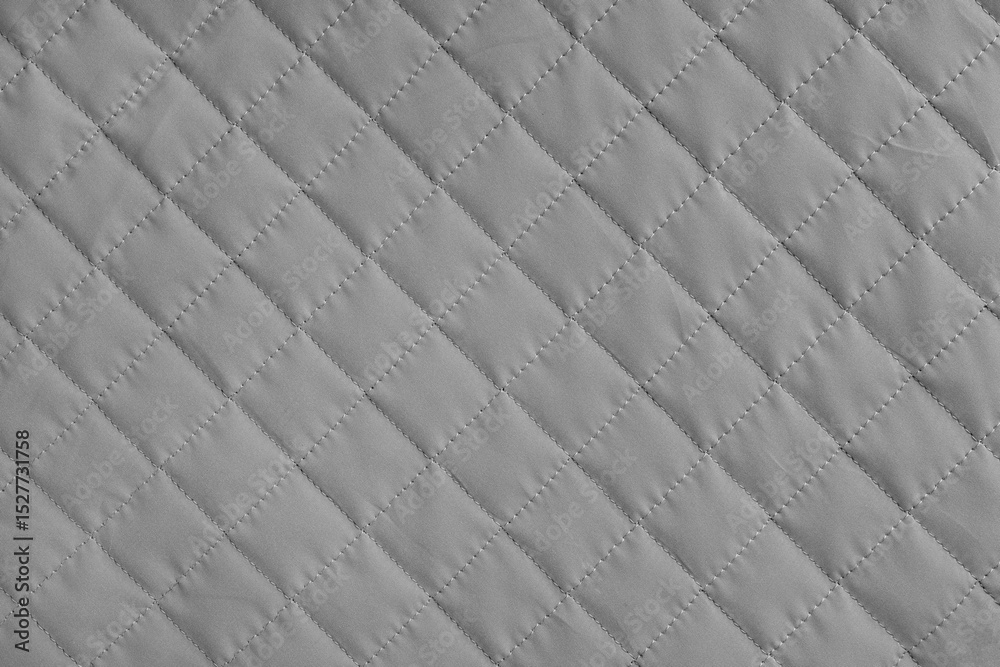 Fototapeta premium Checkered, diamond stitching pattern, gray quilted fabric background. Blanket or puffer jacket, stitch rhombus texture close up, macro. Wallpaper, backdrop.