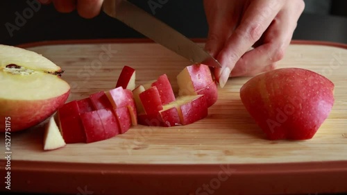 woman’s hands slicing a fresh apple at home on a wooden cutting board