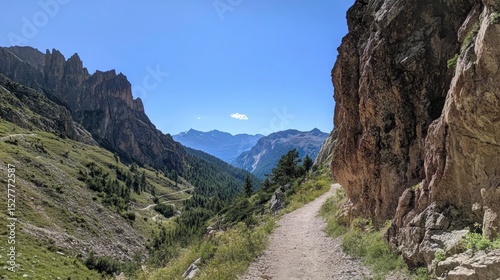 Narrow gravel trail hugging the mountainside in the Dolomites, clear skies and breathtaking panoramic views, no people