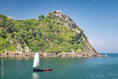 Sailing boat enters Bay of Pasaia, San Sebastian, Spain. Ocean bay, sunny day.