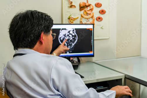 Medical specialist examines digital MRI results at desk. Hospital environment focused on diagnosis and treatment. Concept of precision medicine and modern health technology in action.