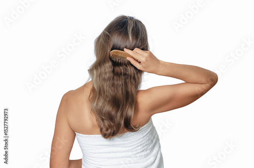 Combing woman's wavy hair after shower with wooden comb on white background. Care for healthy and clean hair.