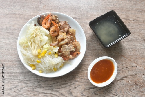 Korean fried slice pork with cabbage and glass noodles on plate dipping spicy sauce couple soup