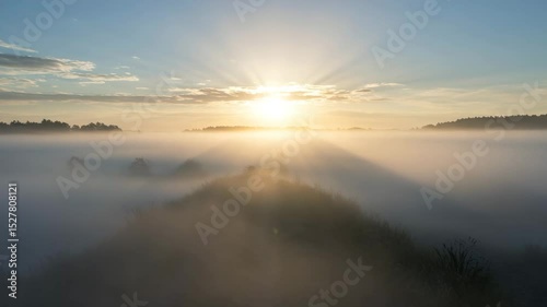 Sunrise over misty landscape with hills and clouds in the distance  