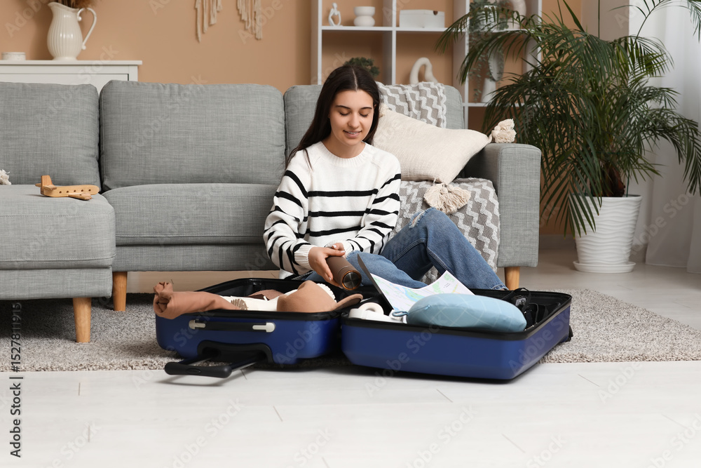 Obraz premium Young woman packing suitcase on floor at home. Travel concept