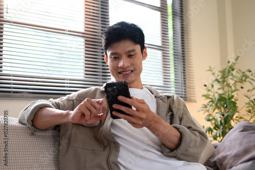 A man is sitting in a room and talking on his mobile phone.