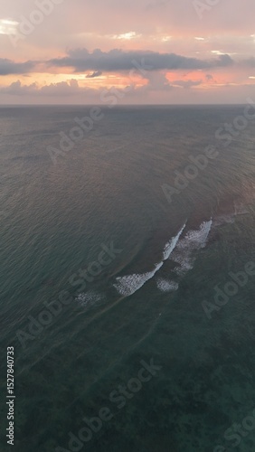 Beautiful cloudy red sunrise over sea with beach, waves and mountains in the background. Impressive structure texture in the sky