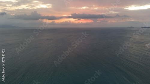 Beautiful cloudy red sunrise over sea with beach, waves and mountains in the background. Impressive structure texture in the sky