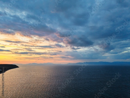 Beautiful cloudy red sunrise over sea with beach, waves and mountains in the background. Impressive structure texture in the sky