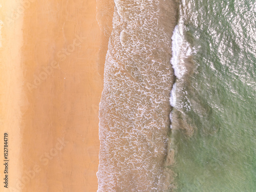Top view beach with waves crashing on sandy shore,Beautiful waves sea surface in summer seascape background,Amazing beach colorful water background