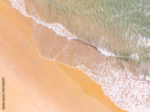 Top view beach with waves crashing on sandy shore,Beautiful waves sea surface in summer seascape background,Amazing beach colorful water background