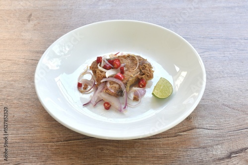 salty dry Indo-Pacific king mackerel fish topping chop shallot and chili with slice lemon salad on plate 
