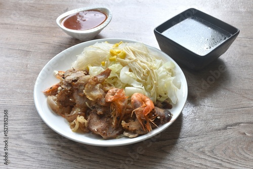 Korean fried slice pork with cabbage and glass noodles on plate dipping spicy sauce couple soup