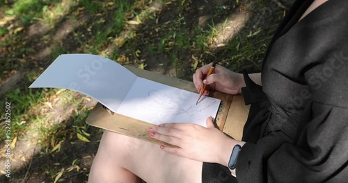 The young woman sketching a floral composition with a pencil during a plein air session